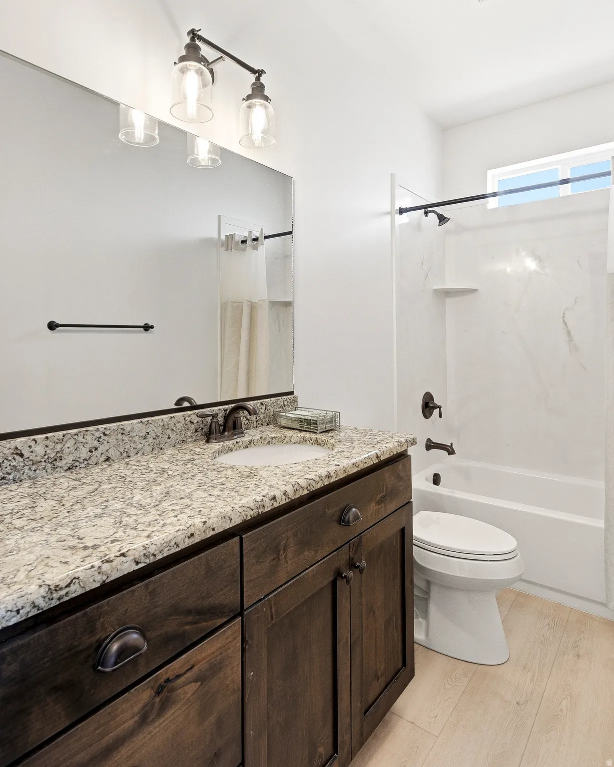 Dark wood-finish vanity with stone countertop, undermount sink, and oil-rubbed bronze fixtures