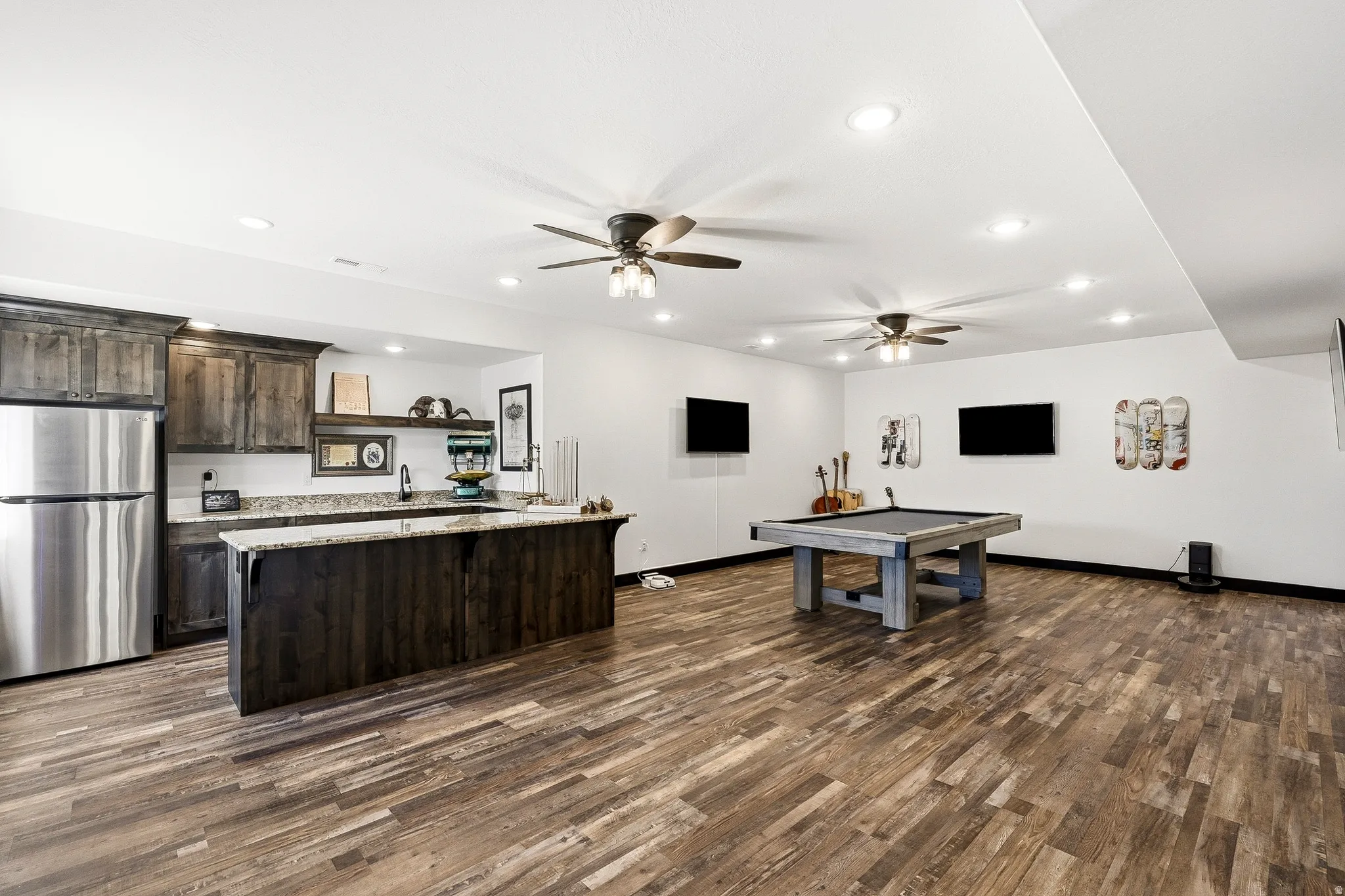 Spacious open area featuring wood-finish flooring, recessed lighting, and ceiling fans