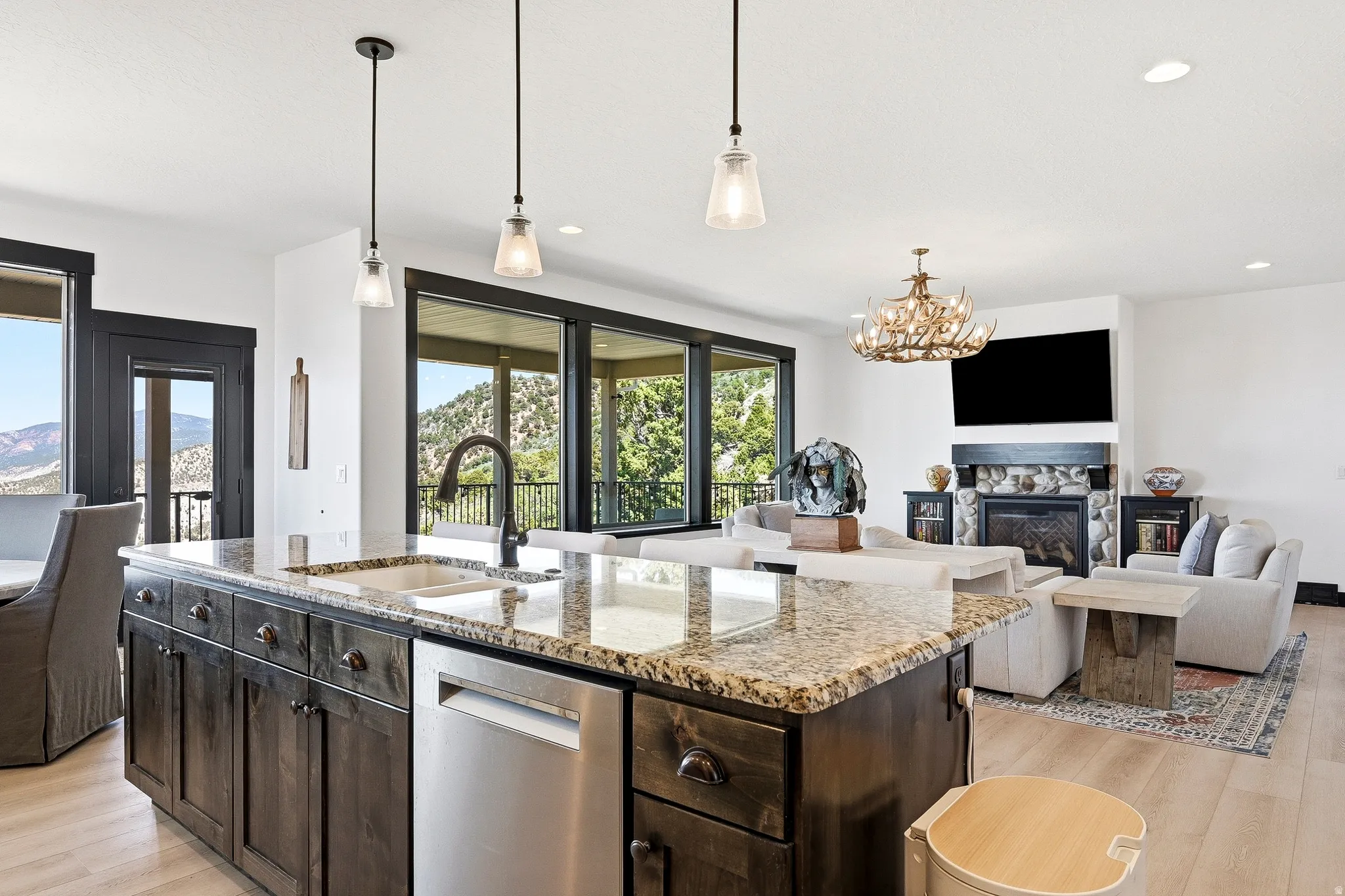 Kitchen island with a built-in sink, stainless steel dishwasher, and pendant lighting