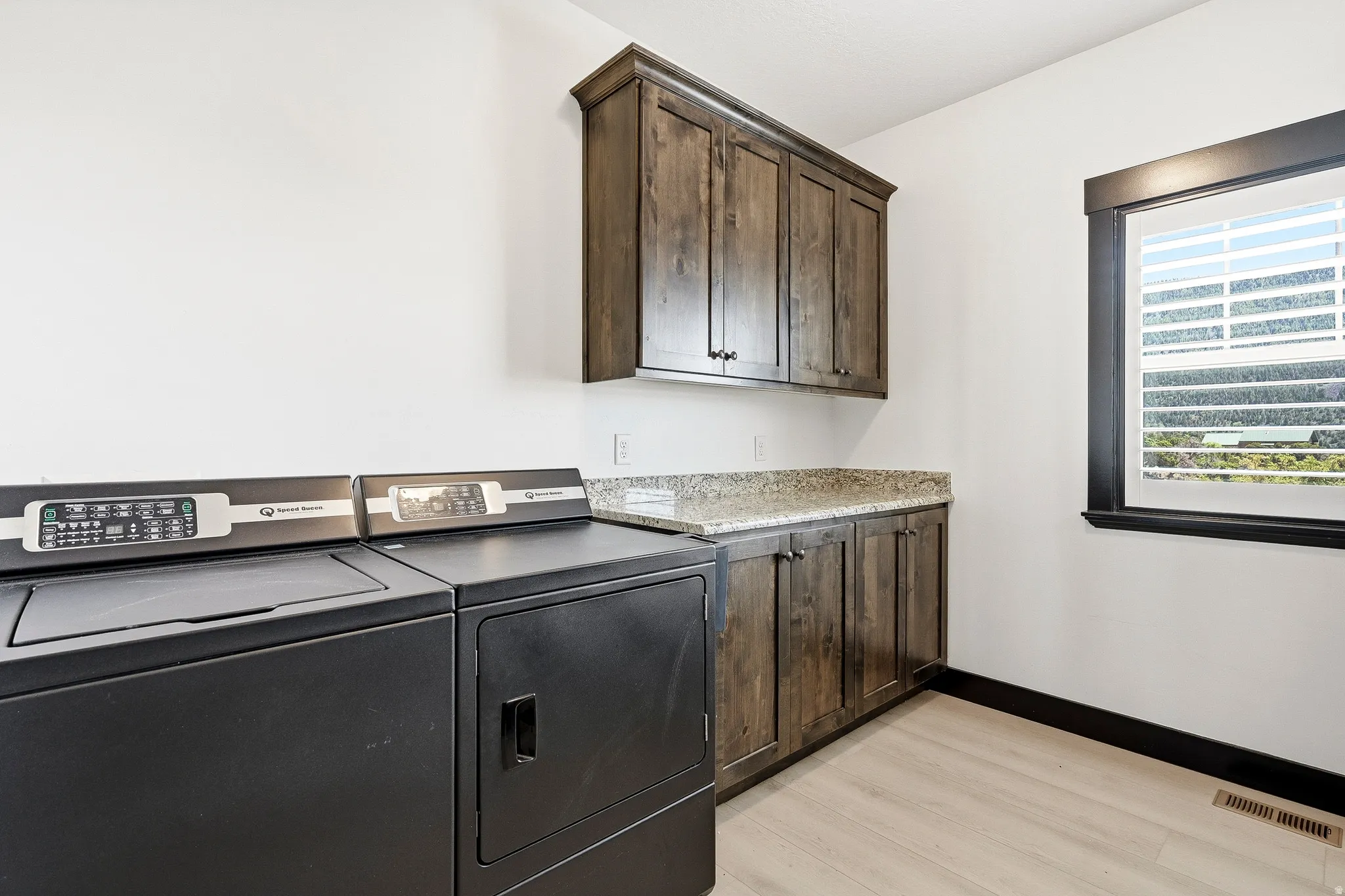 Hardwood-style flooring, built-in cabinetry, stone-look countertop, and a window with dark trim
