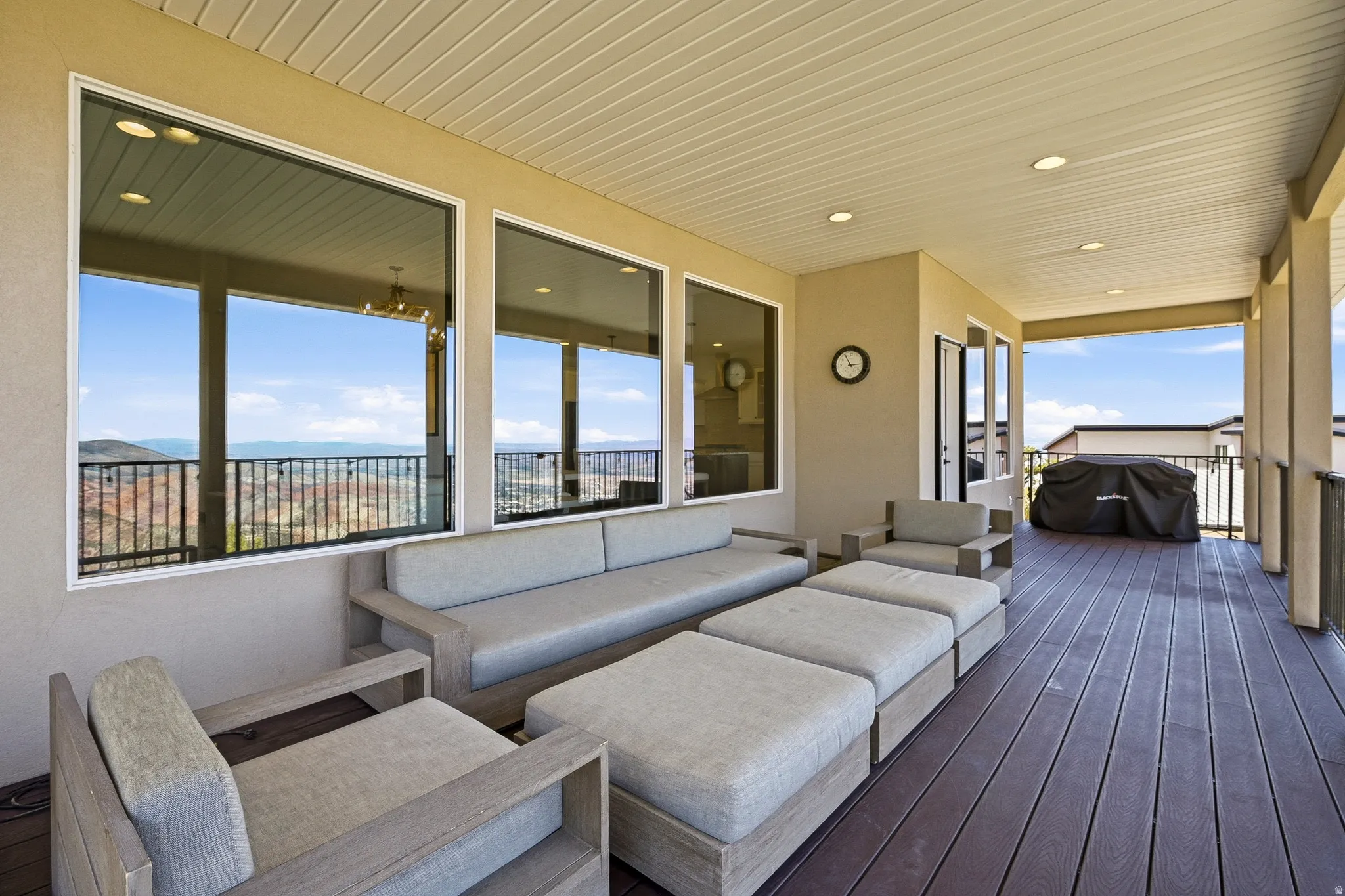 Covered outdoor patio featuring extensive decking, recessed lighting, and expansive windows
