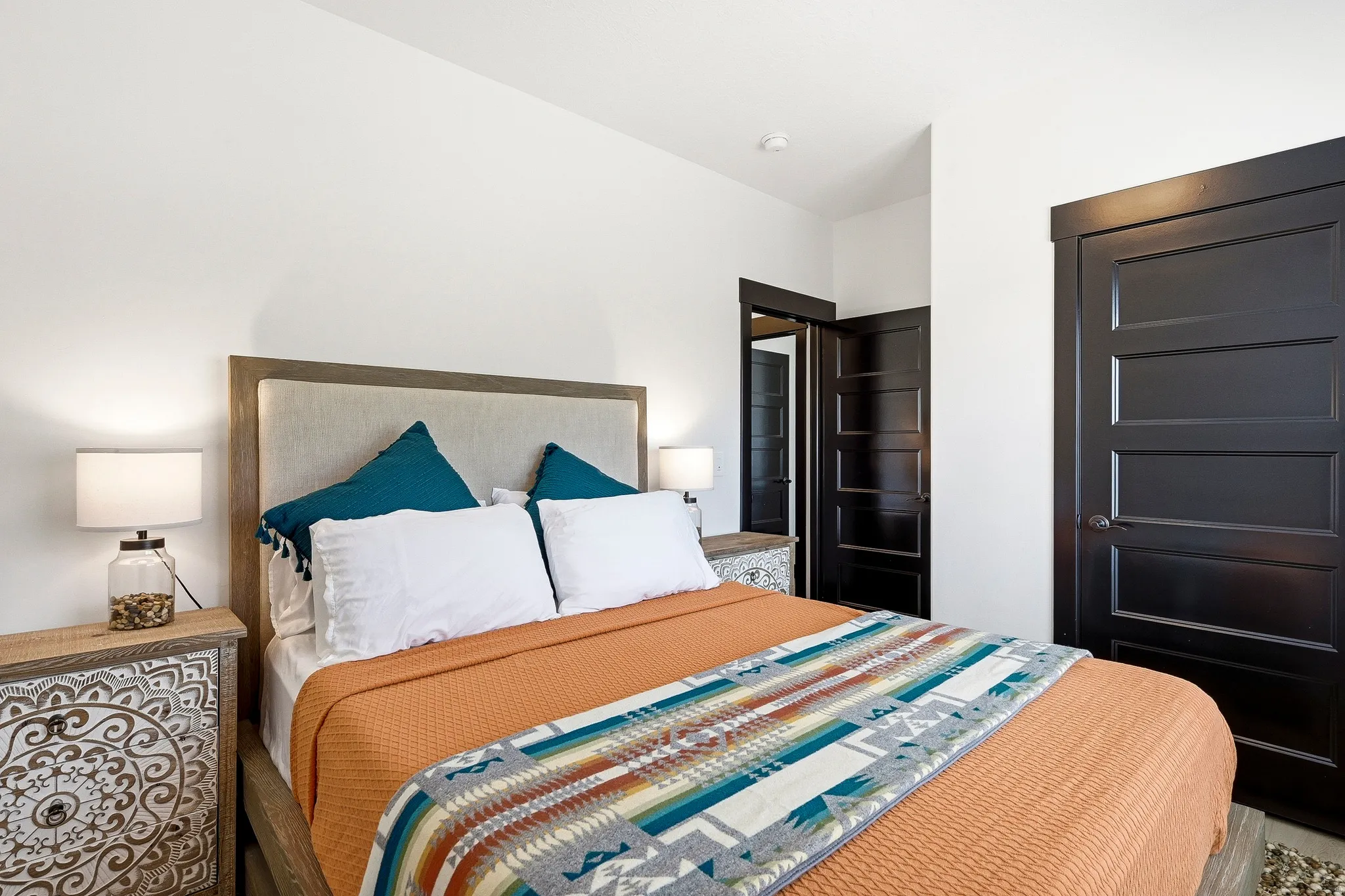 White walls with recessed lighting, dark wood-finish paneled doors, and a wood-finish bed frame with an upholstered headboard