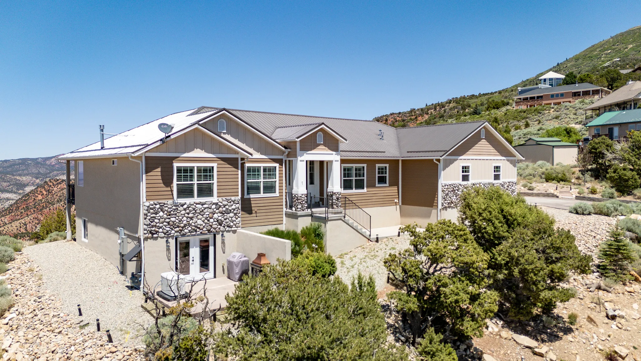 Split-level residence featuring a metal roof, stone facade accents, and a lower-level patio