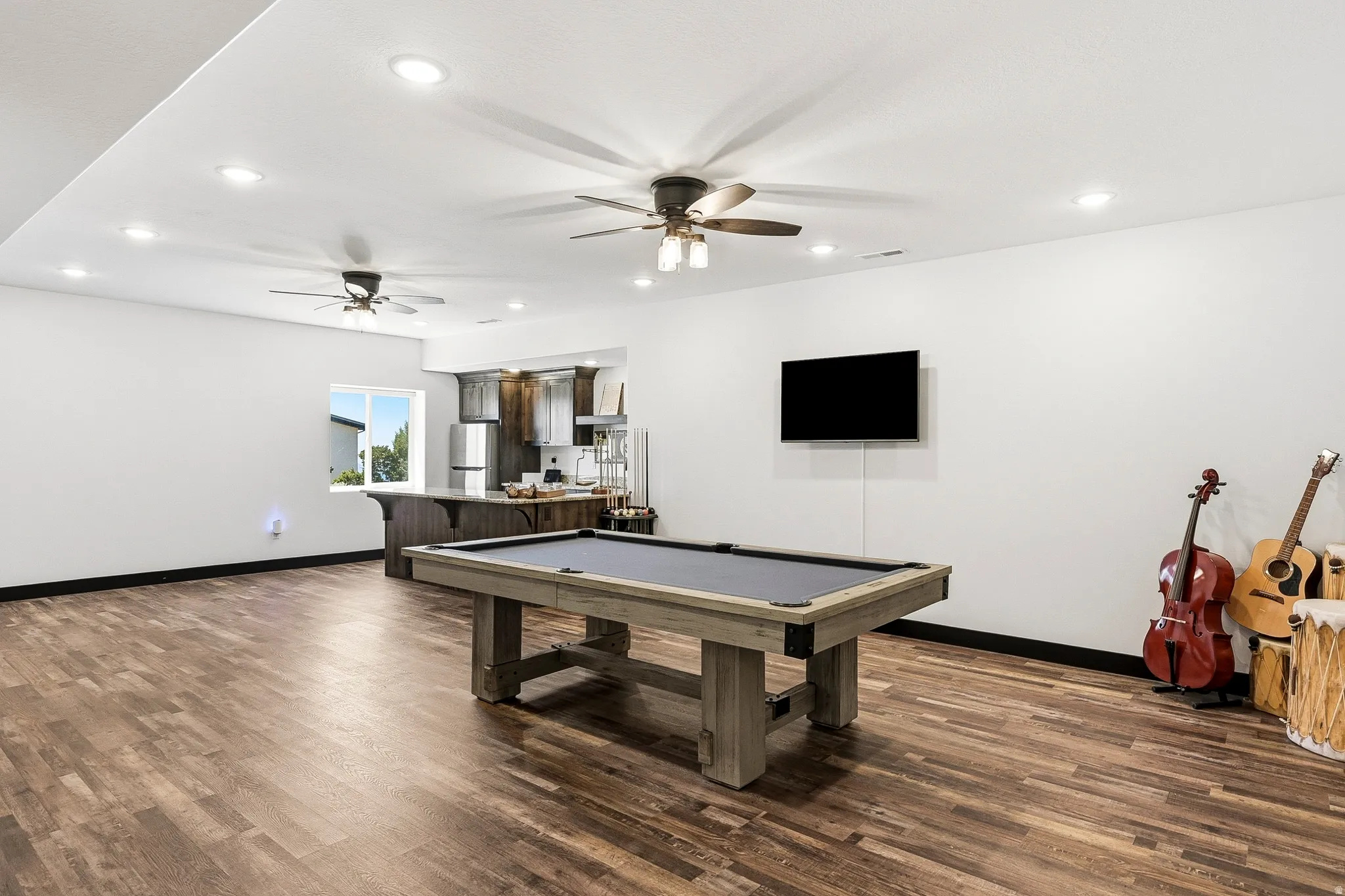 Spacious room featuring wood-finish flooring, recessed lighting, and ceiling fans