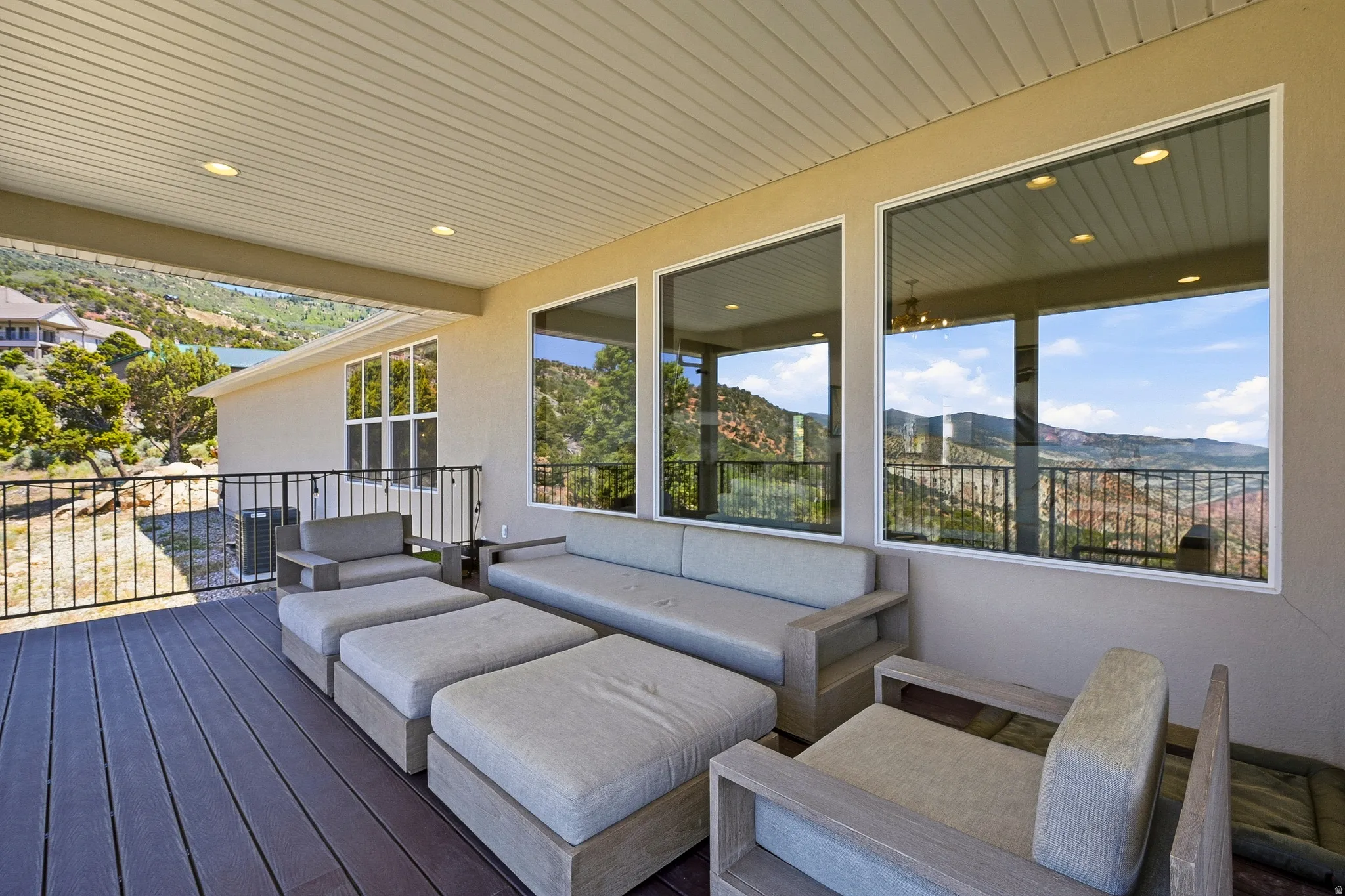 Expansive covered deck featuring composite decking, recessed lighting, and a metal railing