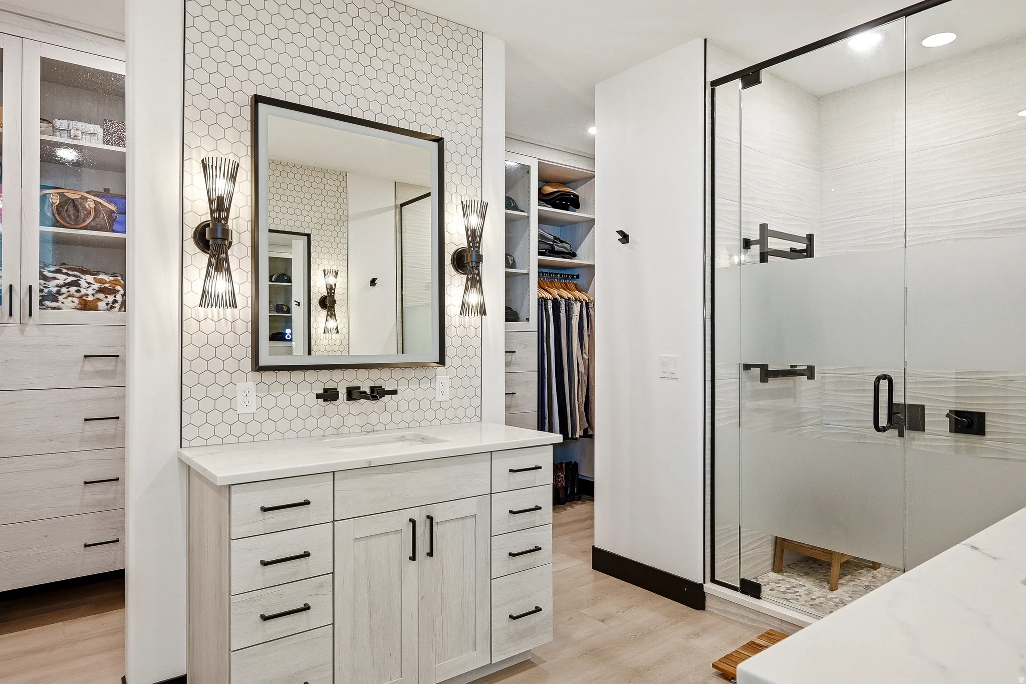 Vanity with hexagonal tile backsplash and black-framed mirror