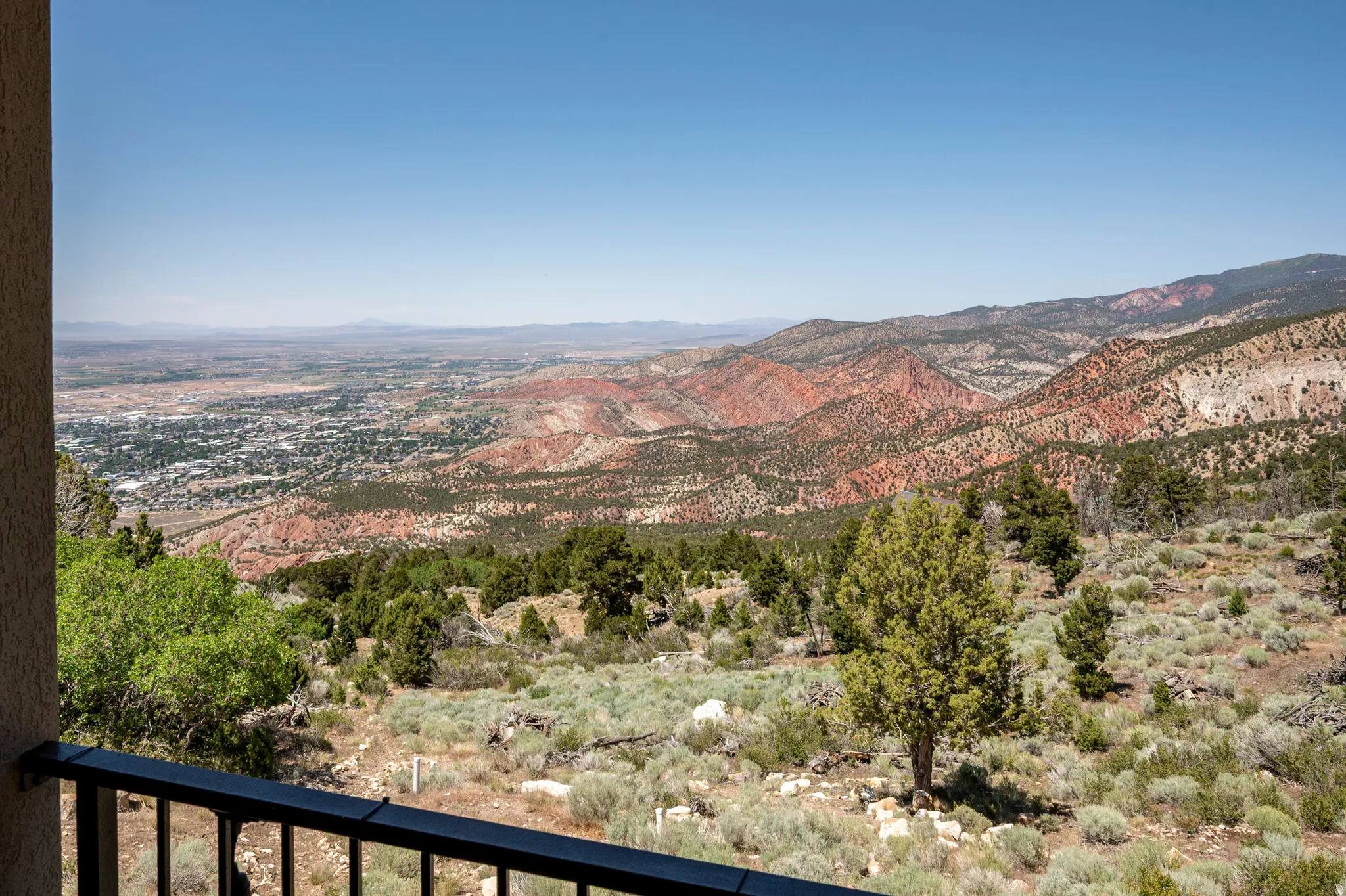 Balcony with a black metal railing framing expansive mountain and valley scenery