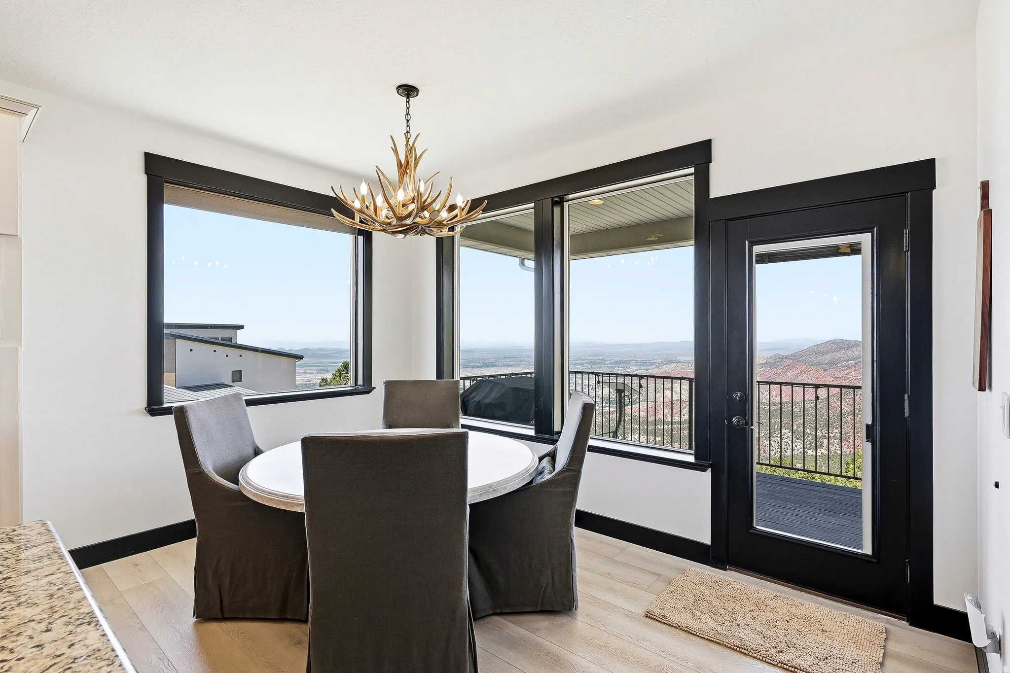 Wood-finish flooring with a glass-paneled door, black trim details, and a decorative antler-style chandelier