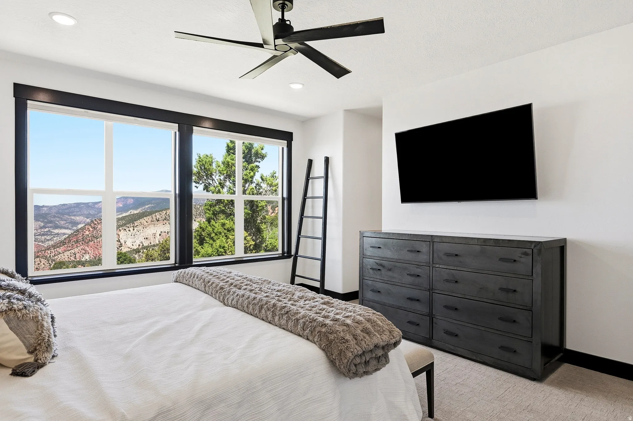 Large windows with dark trim, recessed ceiling lights, and a ceiling fan
