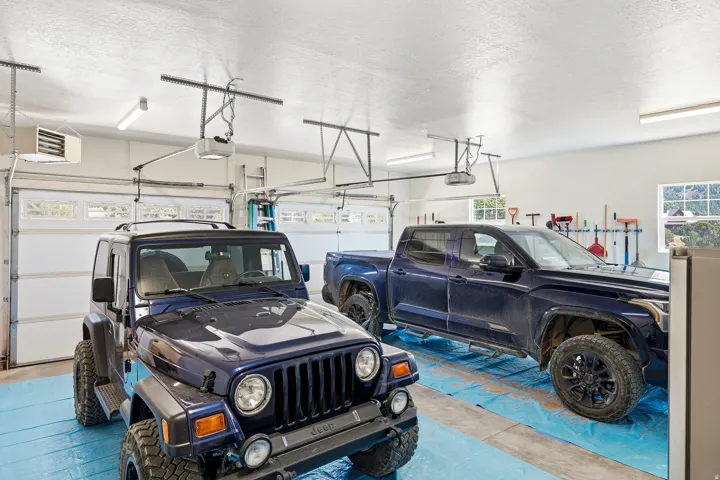Two-car garage with overhead doors, concrete flooring, overhead lighting, and two windows