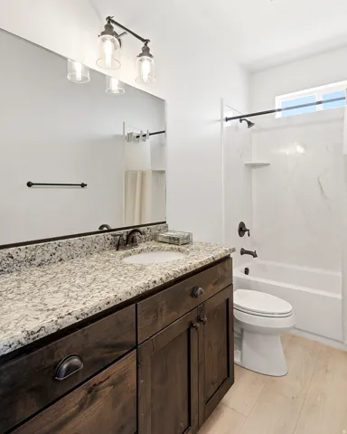 Dark wood-finish vanity with stone countertop, undermount sink, and oil-rubbed bronze fixtures