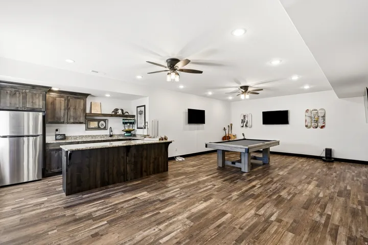 Spacious open area featuring wood-finish flooring, recessed lighting, and ceiling fans