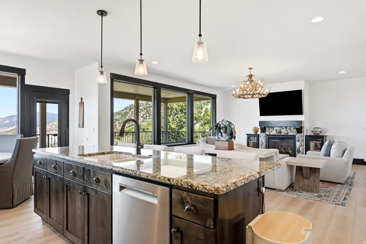 Kitchen island with a built-in sink, stainless steel dishwasher, and pendant lighting