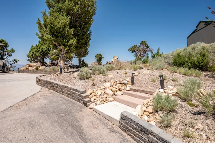Segmented retaining wall, paved driveway, concrete steps, and landscaped hillside