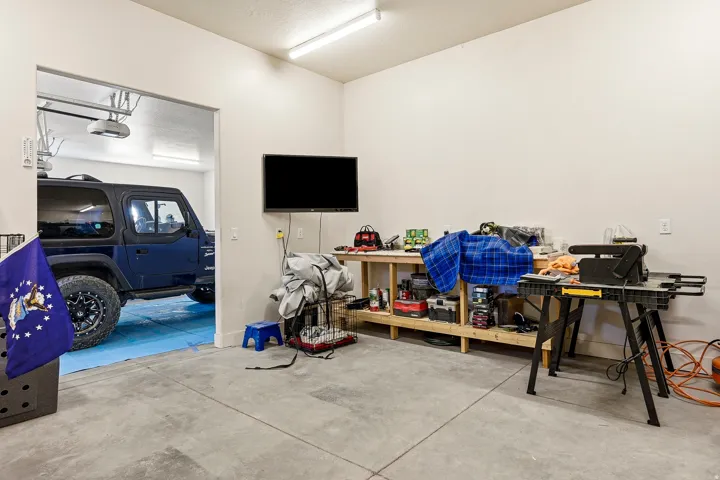 Concrete flooring with a built-in workbench, overhead fluorescent lighting, and white painted walls
