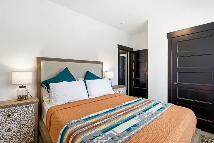 White walls with recessed lighting, dark wood-finish paneled doors, and a wood-finish bed frame with an upholstered headboard