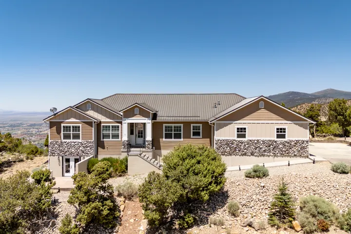 Multi-level residence featuring a metal roof, stone and siding exterior, multiple windows, and a prominent front entrance with stairs