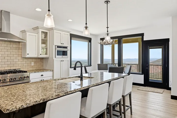 Kitchen featuring granite countertops, a built-in microwave, a stainless steel range hood, pendant lighting, and light wood-finish flooring