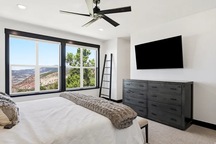 Large windows with dark trim, recessed ceiling lights, and a ceiling fan