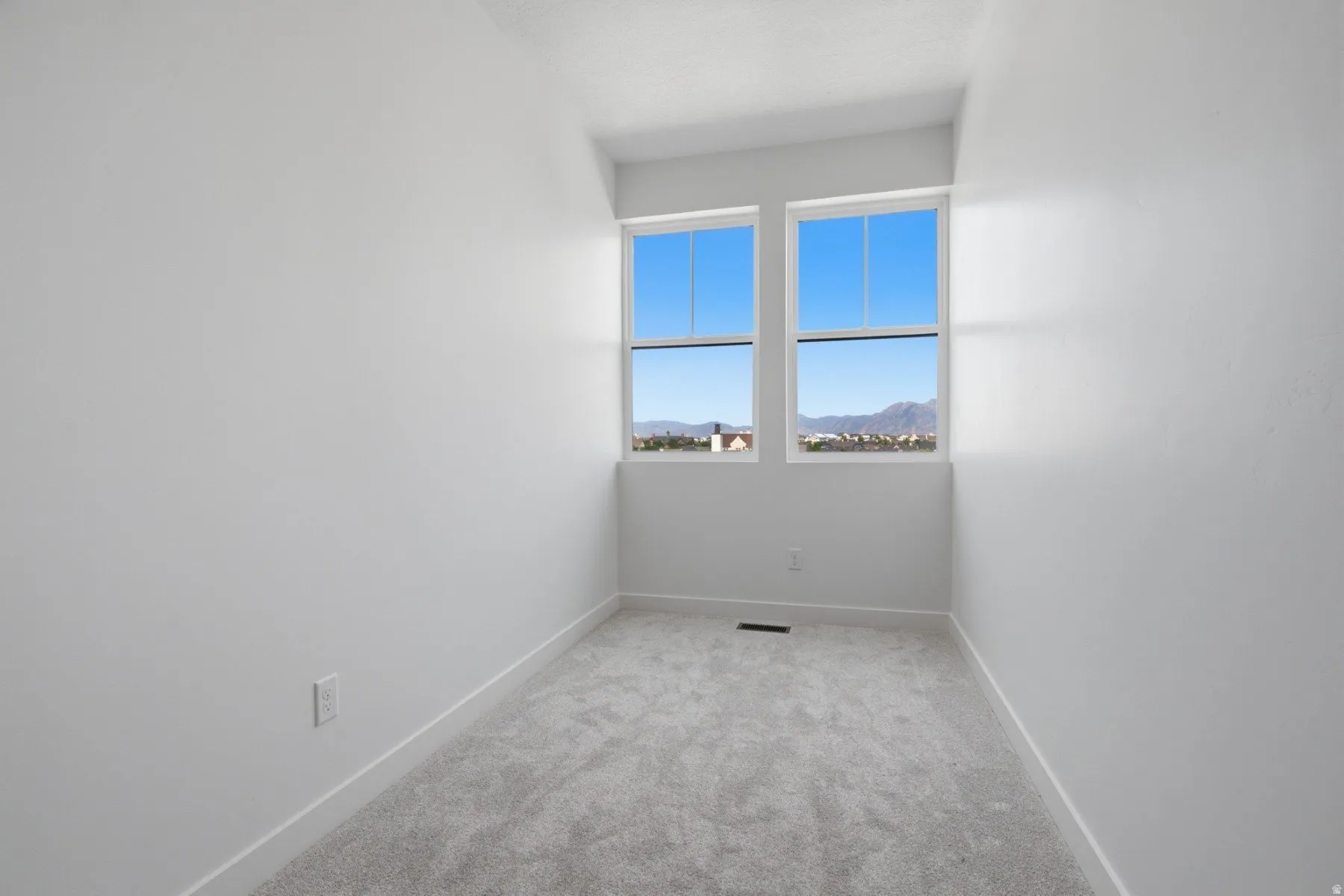 Two large windows, wall-to-wall carpeting, and bright white walls