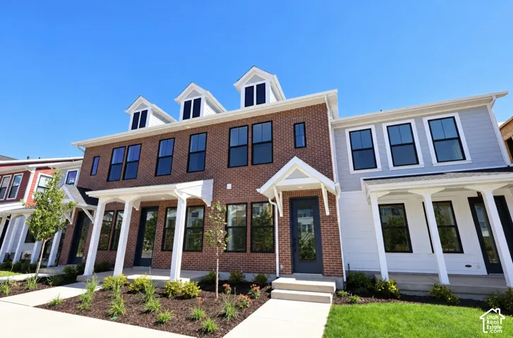 Brick and siding exterior with multiple dormer windows, covered front entrance, and established landscaping