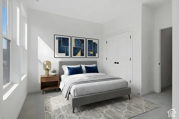 Crisp white walls, multiple windows, a paneled closet door with black hardware, and carpeted flooring