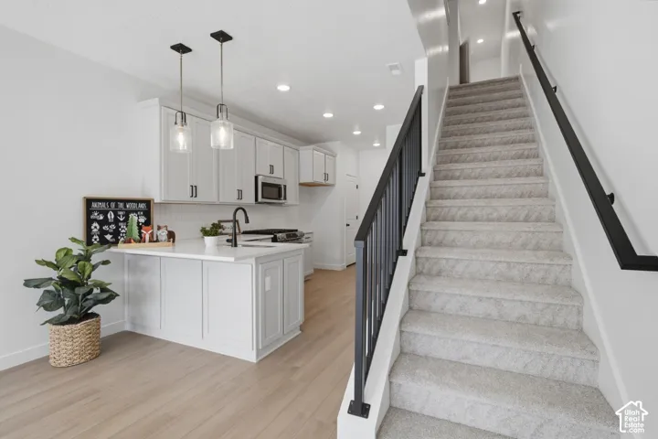 Kitchen with white cabinetry, stainless steel microwave, and white subway tile backsplash