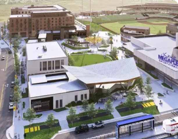 Mixed-use development featuring commercial structures, multi-story residential buildings, a public green space, and a nearby stadium
