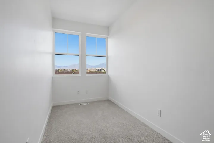 Two large windows, white walls, and gray carpeted flooring
