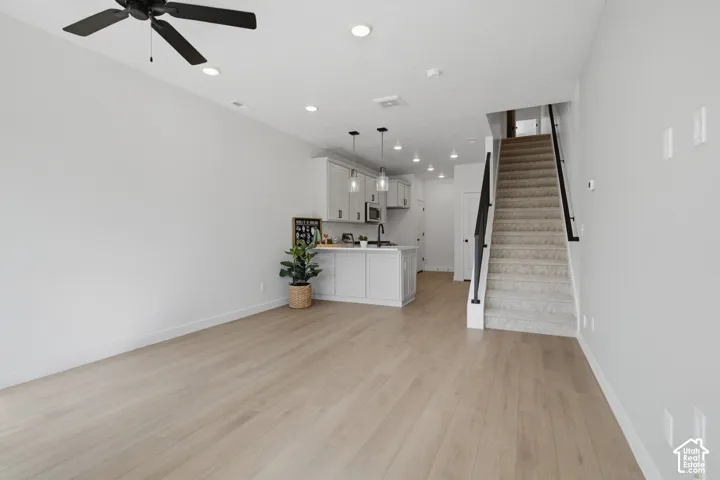 Open-concept living area featuring wood-finish flooring, recessed lighting, and a ceiling fan