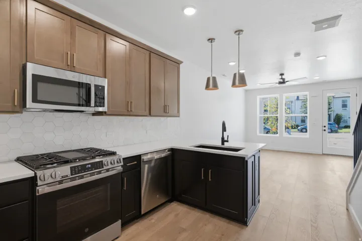 Kitchen with two-tone cabinetry, stainless steel appliances, and hexagon tile backsplash