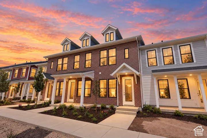 Brick and siding exteriors, multiple dormer windows, covered entryways with white columns, concrete walkways, and planted landscaping