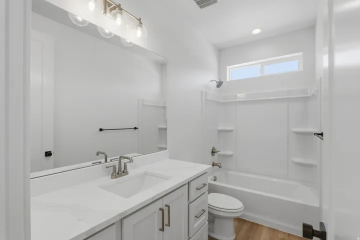Bathroom featuring a single vanity with a white countertop, an undermount sink, and light gray cabinetry