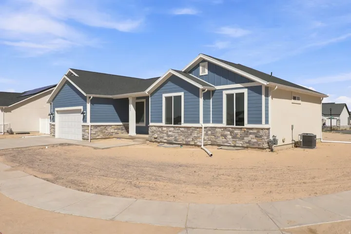Contemporary home with blue siding, stone veneer accents, an attached garage, and a concrete driveway