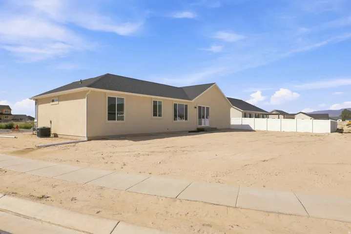Cream stucco exterior with multiple windows, a sliding glass door, and a dark shingle roof