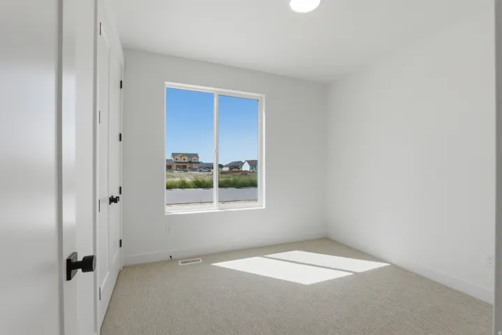 Bright room with neutral carpeting, white walls, and a large window