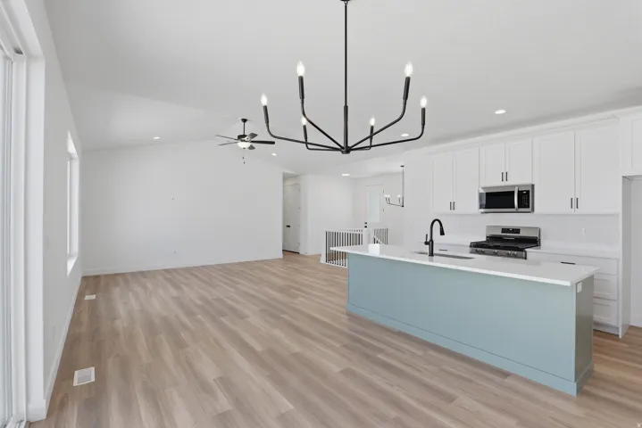 Open concept living area featuring vaulted ceilings, wood-finish flooring, and a modern chandelier