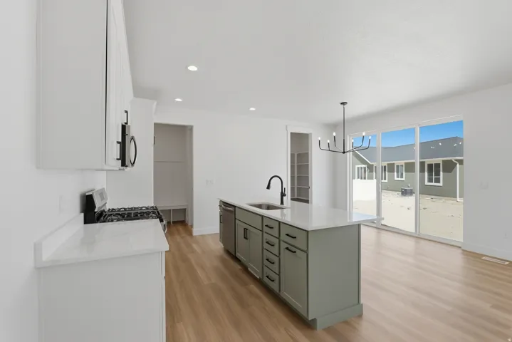 Kitchen featuring white upper cabinetry, a central island with gray lower cabinetry, a stainless steel gas range, and a single basin sink