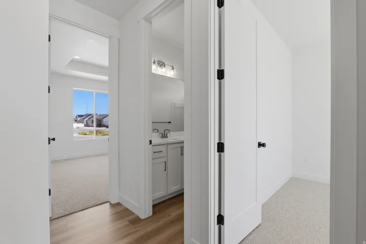 Tray ceiling with recessed lighting, large window, wood-finish flooring, white vanity with dual sinks, and modern light fixtures