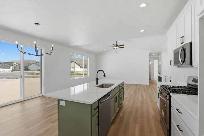 Kitchen with a center island, white countertops, built-in stainless steel appliances, wood-finish flooring, and white cabinetry