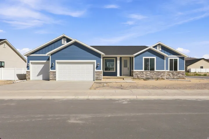 Exterior featuring blue siding, stone facade, a two-car garage, and multiple windows