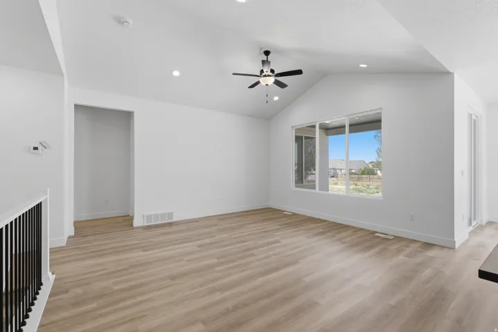 Vaulted ceilings with recessed lighting, wood-finish flooring, a contemporary ceiling fan, and large windows