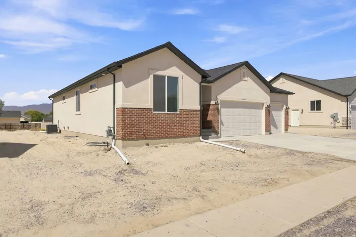 Stucco and brick exterior with a dark shingle roof, featuring multiple garage doors and a concrete driveway
