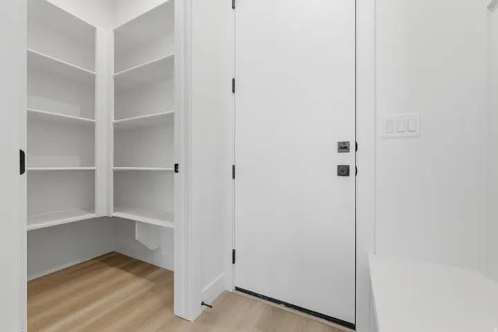 Built-in pantry shelving, wood-finish flooring, white solid core door, contemporary matte black hardware, built-in bench