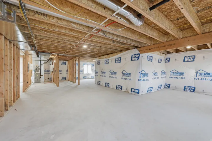 Unfinished basement featuring exposed wood joists, concrete flooring, and roughed-in wall framing