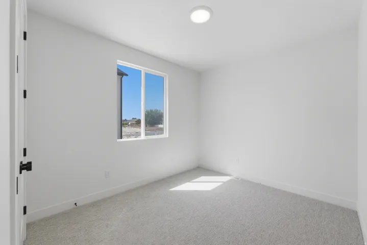 White painted interior with a single window, recessed ceiling light, and gray carpeting
