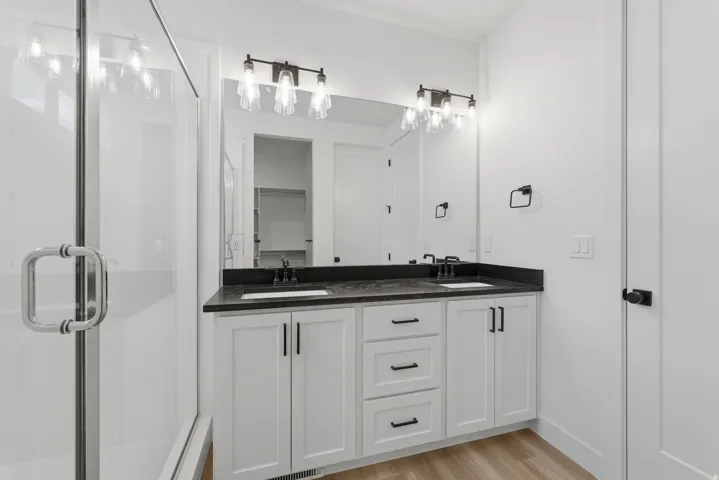 Dual vanity with dark countertops, white cabinetry, and matte black hardware