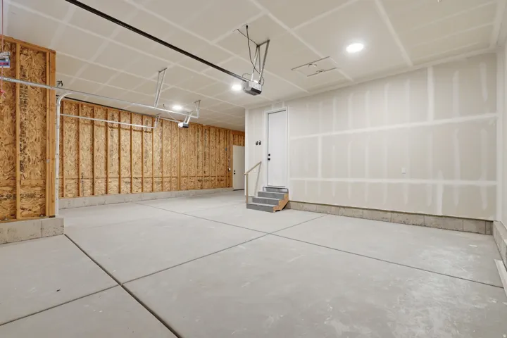 Spacious garage with exposed wood framing, concrete flooring, and built-in overhead lighting