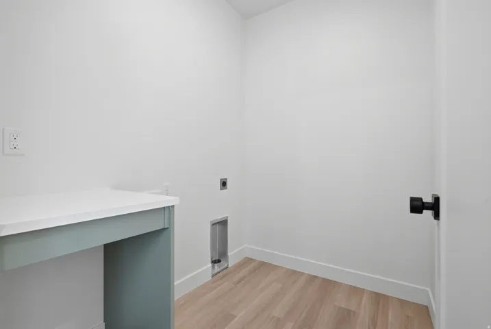 Light wood-finish flooring, white walls, and a built-in counter with a white surface