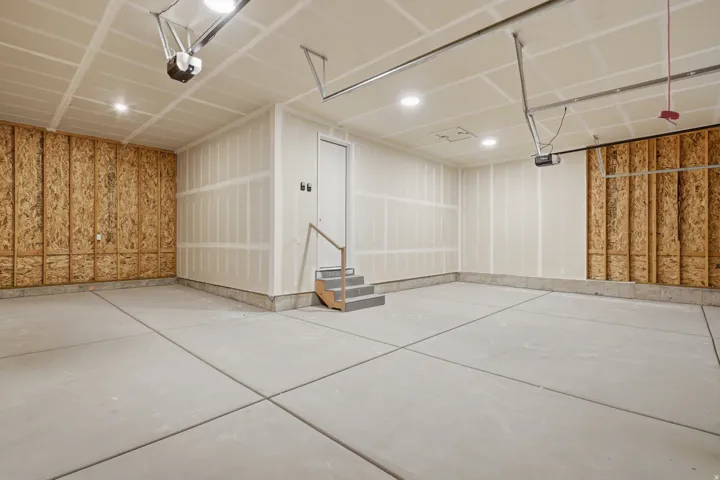 Expansive garage with unfinished wood paneling, concrete flooring, and recessed lighting